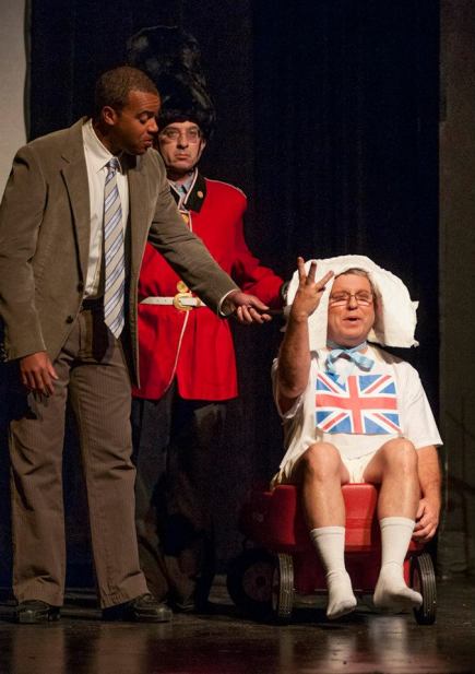 Justin Stewart interviews the new-born royal baby, played by David Spear, while a royal sentry played by Ben Pollock stands guard.